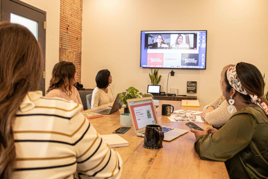 People in a conference room looking at a Zoom call on a TV screen on the wall.