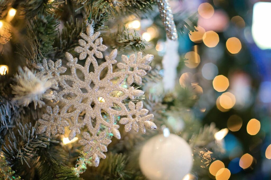 A white snowflake ornament hanging on a Christmas tree