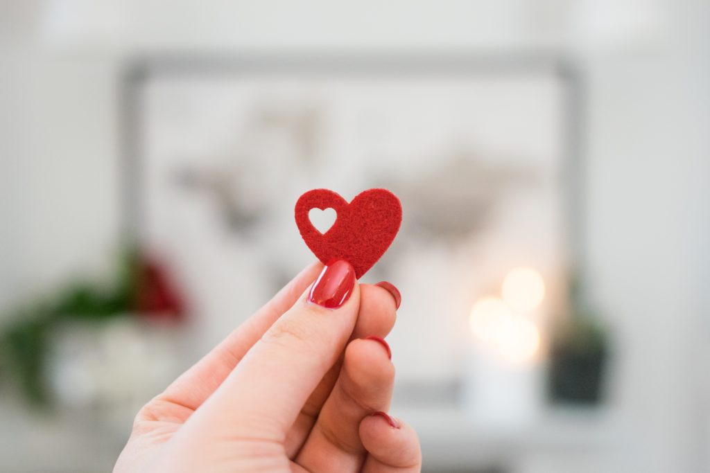 person holding pink heart ornament