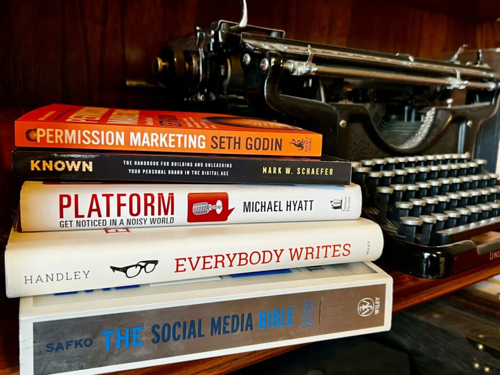 A stack of marketing books sitting next to a typewriter.