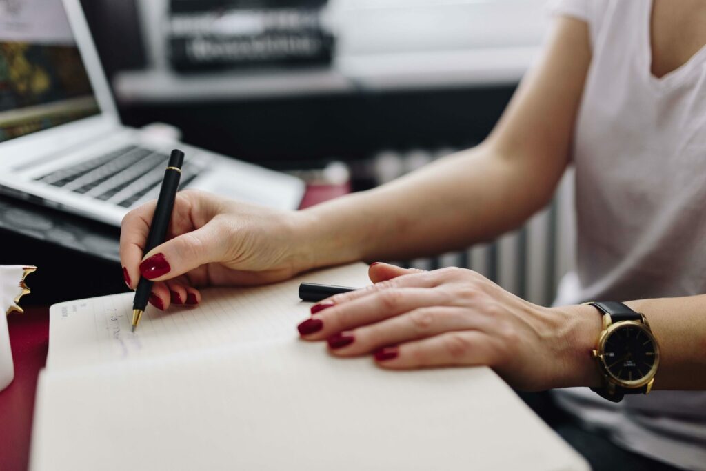 A woman's hands as she writes in a notebook.