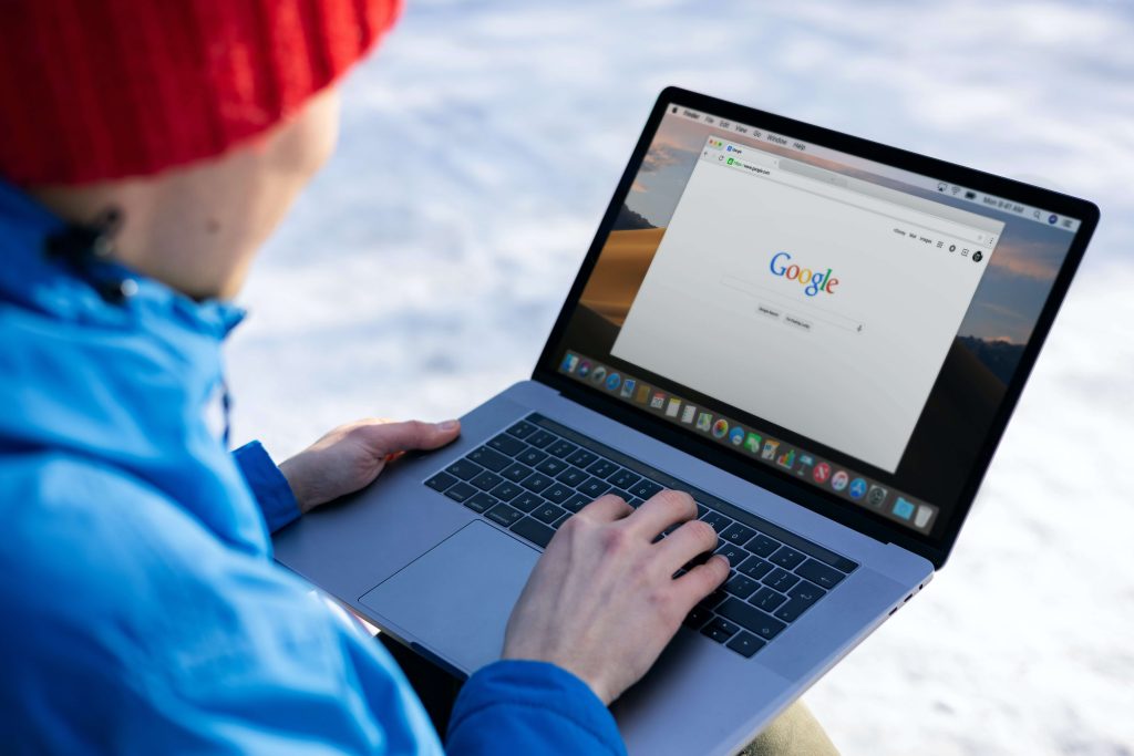 A person in a red stocking cap searching Google on a laptop