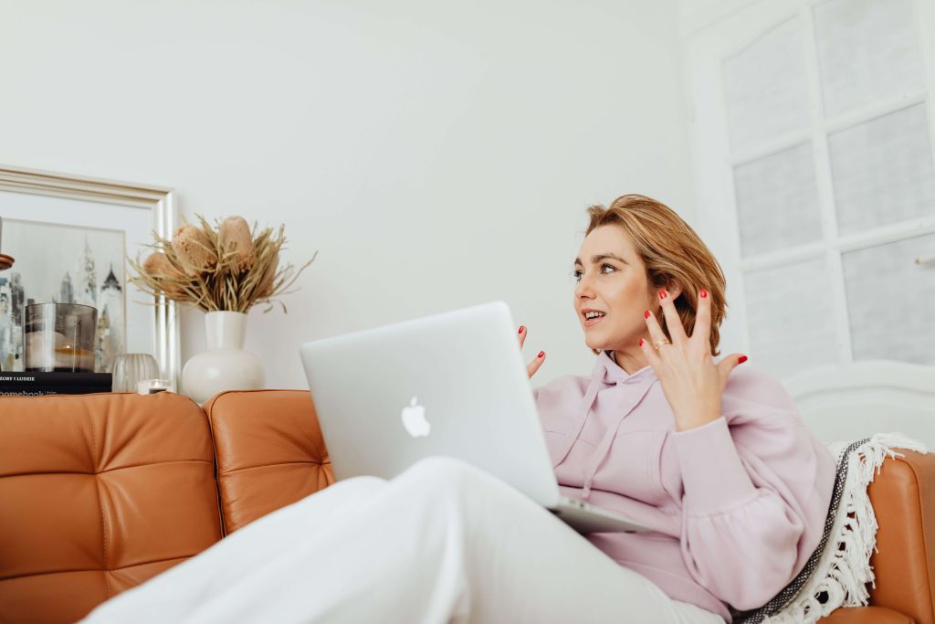 A woman sitting on a sofa and talking with someone on her laptop screen