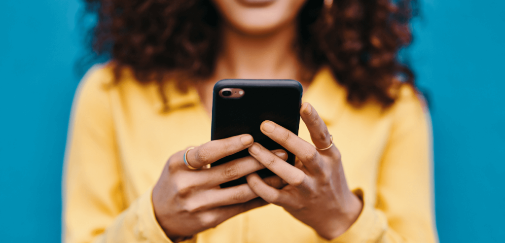 Close-up of a woman holding a cell phone viewing social media advertising